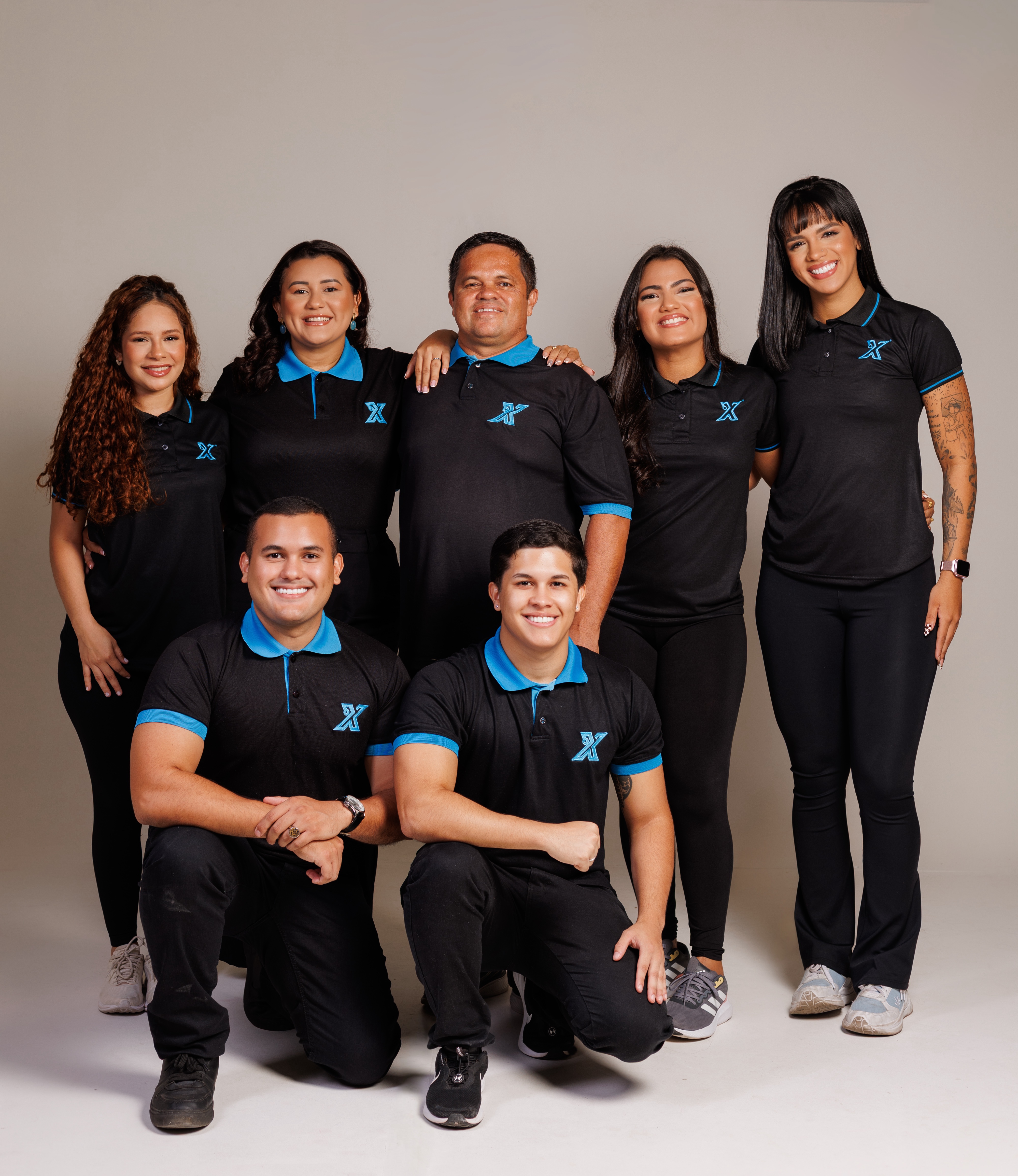 A equipe completa da Extra Serviços: sete profissionais uniformizados com camisetas polo pretas com o X azul, em pose de grupo